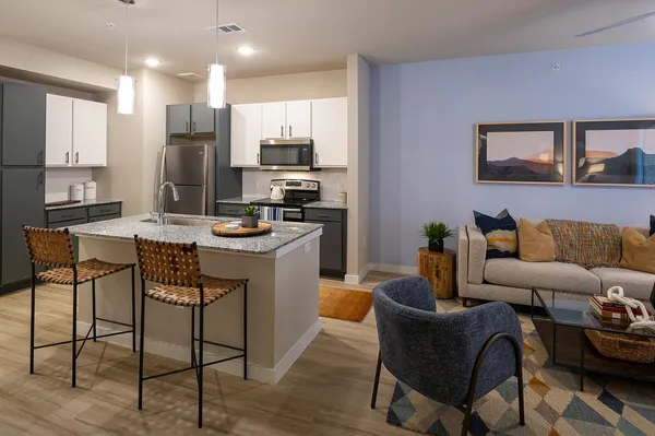 a living room with stainless steel appliances kitchen island granite countertop furniture a refrigerator a stove a sink a dining table and chairs