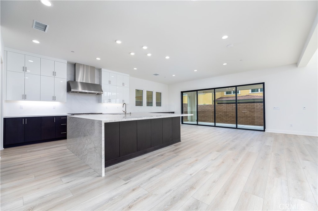 108 Coldwater Irvine, CA 92602 - Photo 3 of 36 a large white kitchen with kitchen island a sink wooden floor and a large window