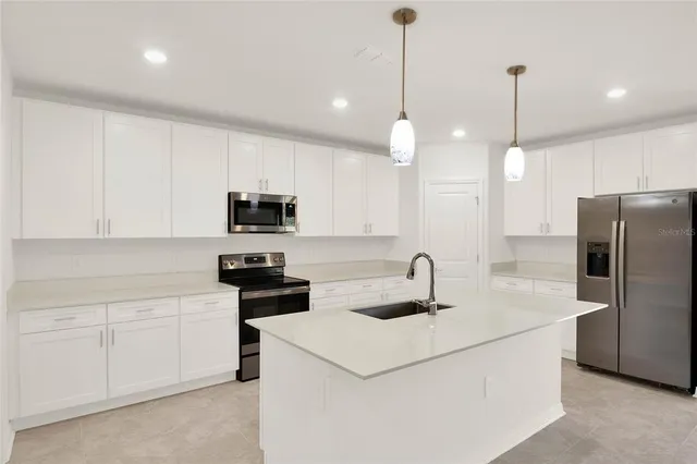 a kitchen that has a microwave a stove a sink a refrigerator and cabinets