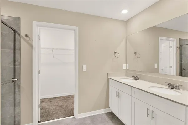 a spacious bathroom with a shower a sink and a mirror