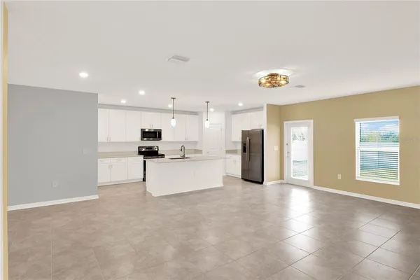 a view of a kitchen with kitchen island a sink wooden floor and a refrigerator