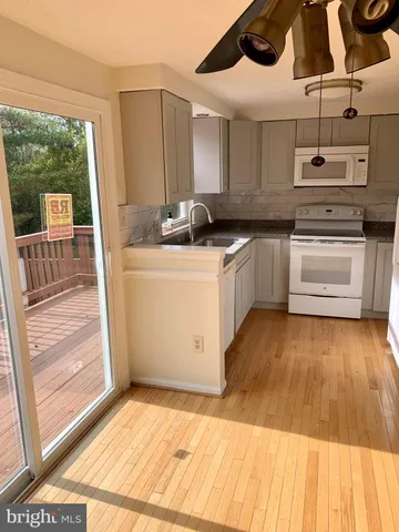 a kitchen with stainless steel appliances kitchen island granite countertop a stove a sink and white cabinets