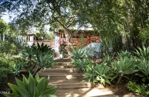 a backyard of a house with large trees and outdoor seating