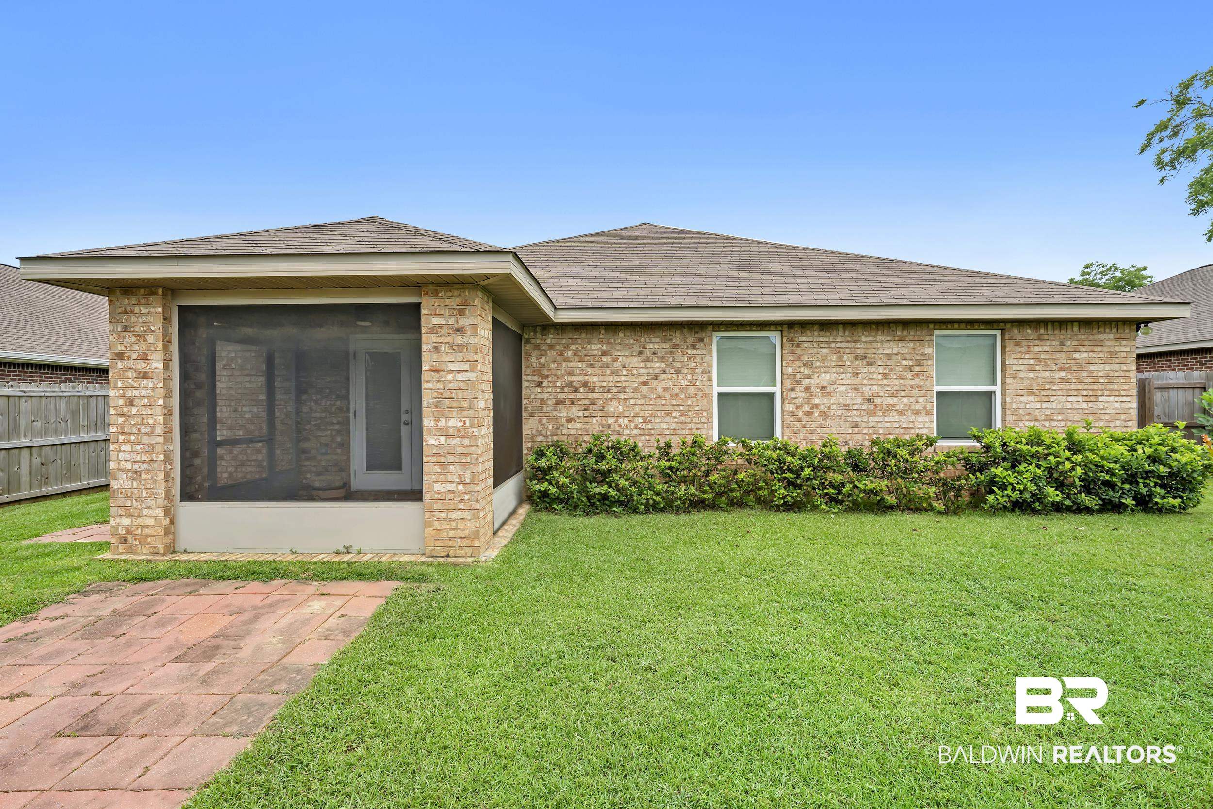 1704 Abbey Loop Foley, AL 36535 - Photo 31 of 38 Rear exterior featuring a brick facade, screened patio, and a concrete paver walkway
