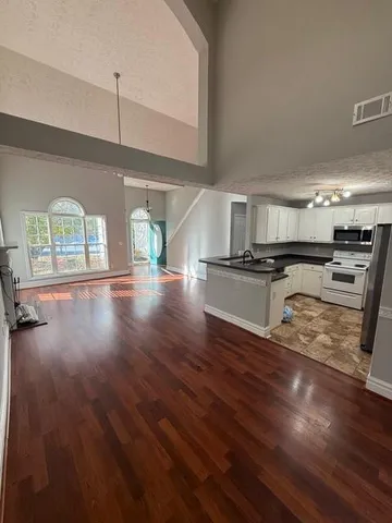 a view of a kitchen with wooden floor and an empty room