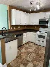 a kitchen with granite countertop a sink a stove and cabinets