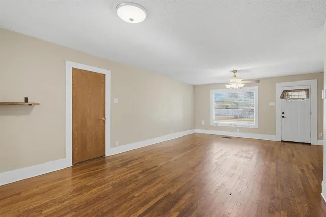 an empty room with wooden floor cabinet and windows