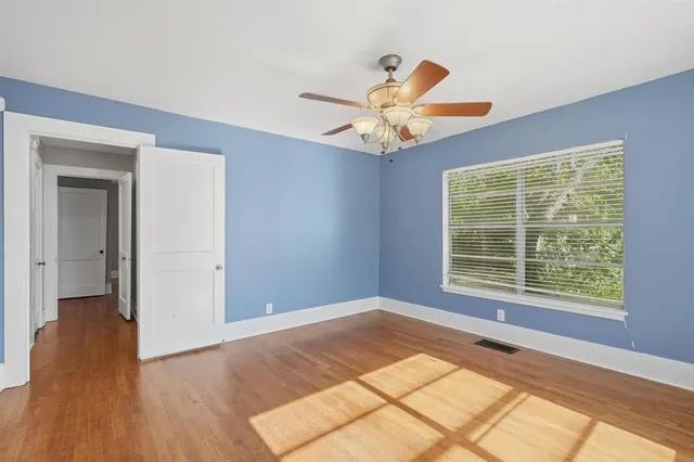 a view of an empty room with a window and wooden floor