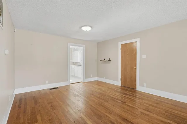 a view of an empty room with wooden floor and closet