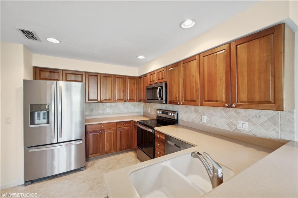 22931 Rosedale Drive, Unit 101 Estero, FL 34135 - Photo 14 of 35 a kitchen with stainless steel appliances granite countertop a refrigerator a sink a stove a washer dryer and a refrigerator