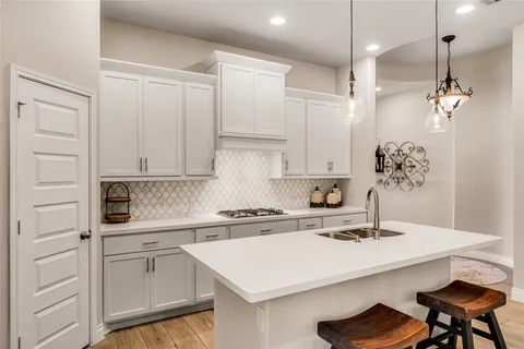 a kitchen with stainless steel appliances kitchen island granite countertop a table chairs sink and cabinets