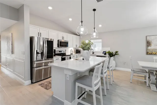 a kitchen with microwave a refrigerator and chairs