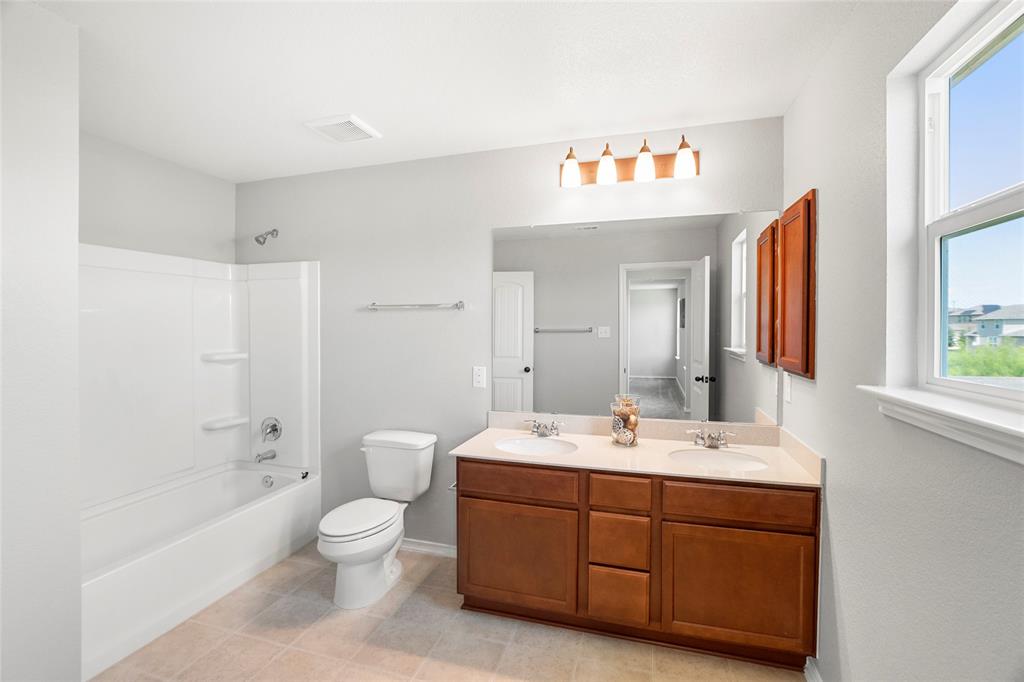 117 West Point Way Elgin, TX 78621 - Photo 13 of 21 Natural light streams into this functional bathroom showcasing a wood vanity and tiled flooring.