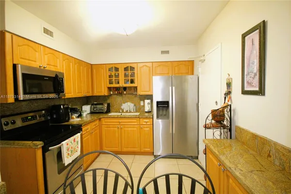 a kitchen with a refrigerator a stove top oven a sink and a dining table with wooden floor