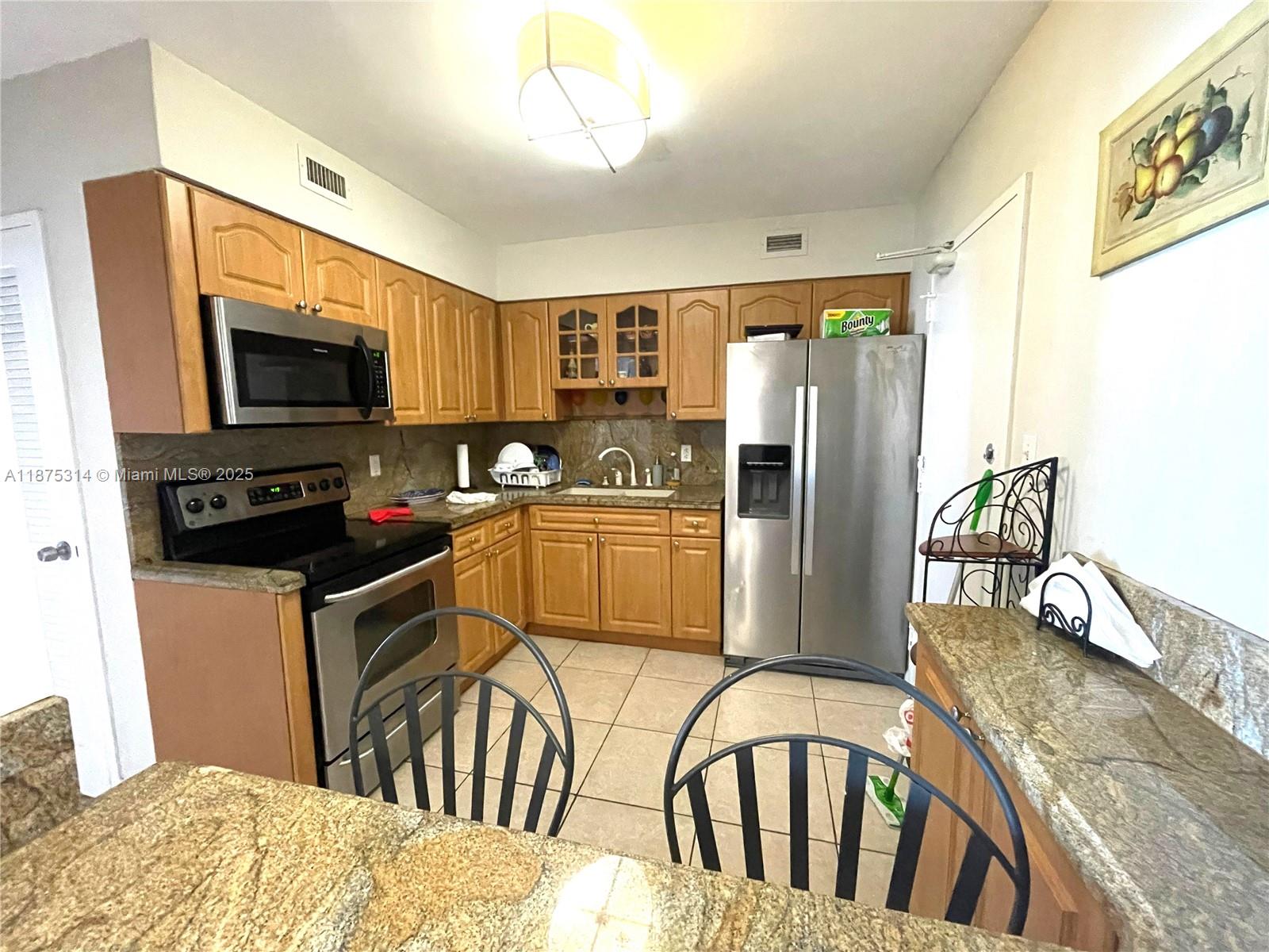 5161 Collins Avenue, Unit 603 Miami Beach, FL 33140 - Photo 8 of 56 a kitchen with stainless steel appliances granite countertop a refrigerator a stove top oven a sink and dishwasher