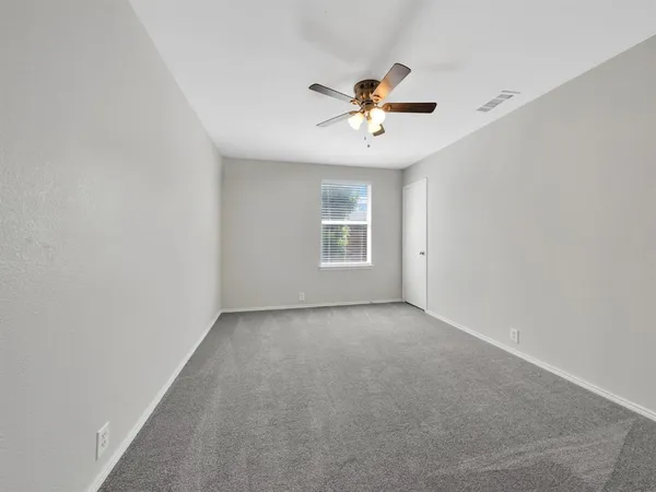 an empty room with windows and ceiling fan