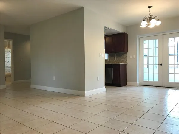 an empty room with kitchen chandelier and windows