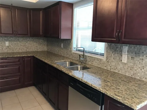 a kitchen with granite countertop a sink a stove and cabinets