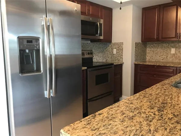 a kitchen with granite countertop a refrigerator and a stove top oven