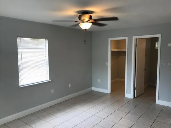 a view of an empty room with window chandelier fan