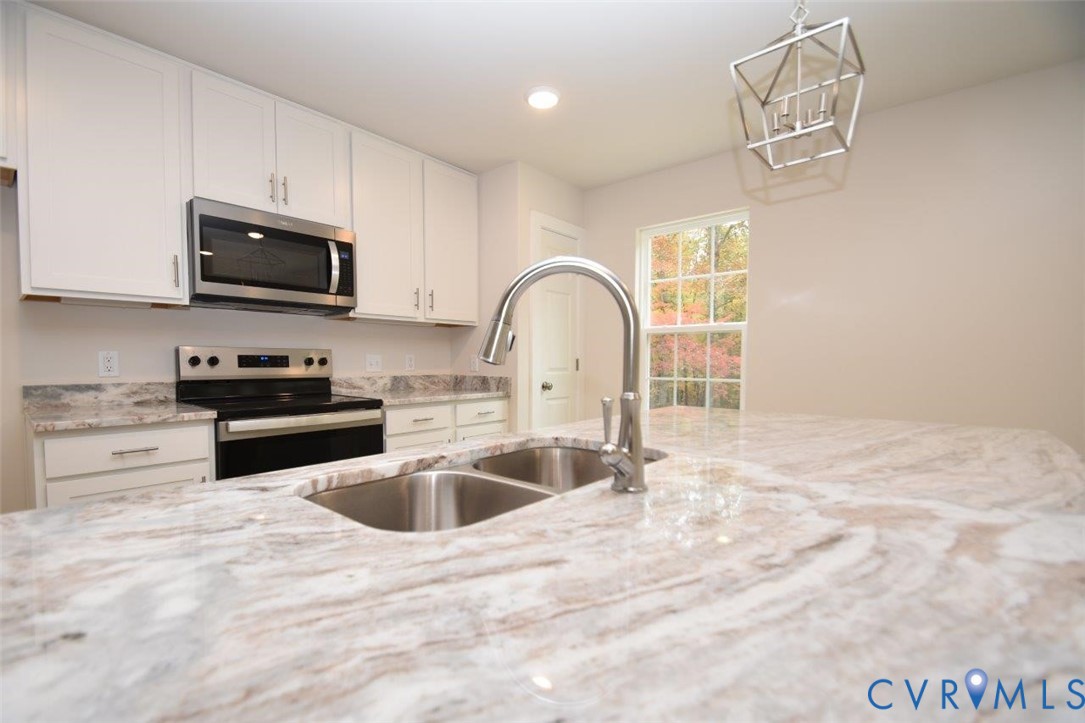 375 Amick Road Louisa, VA 23093 - Photo 9 of 25 a kitchen with granite countertop a sink and a stove top oven with wooden floor
