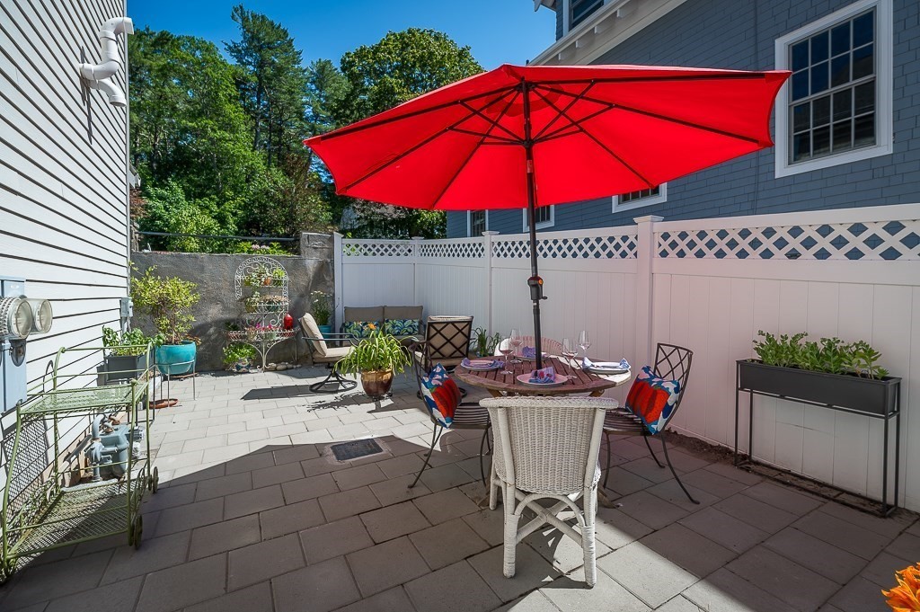 56 Summer Street, Unit A Manchester, MA 01944 - Photo 26 of 35 a patio with a table and chairs under an umbrella