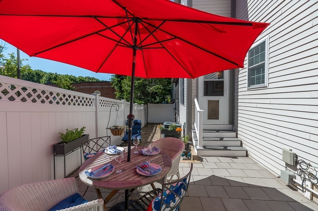 56 Summer Street, Unit A Manchester, MA 01944 - Photo 27 of 35 a view of a patio with table and chairs under an umbrella