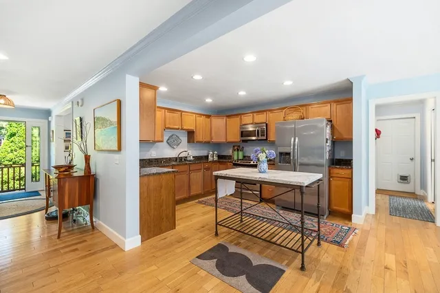 a living room with stainless steel appliances kitchen island granite countertop furniture and a wooden floor