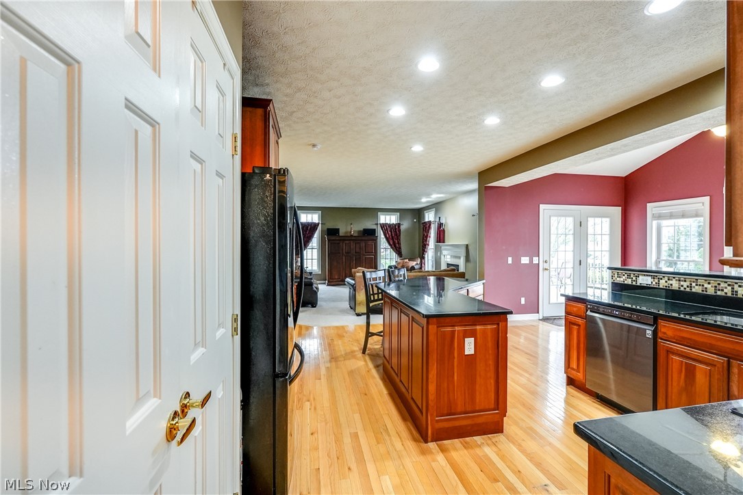 4561 Ridgestone Way Medina, OH 44256 - Photo 11 of 50 Kitchen featuring a large granite center island, light hardwood flooring, black fridge, and stainless steel dishwasher