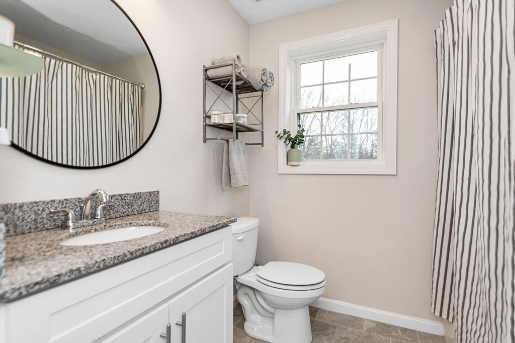 69 Riley Road, Unit 69 Tyngsboro, MA 01879 - Photo 14 of 42 a bathroom with a granite countertop sink mirror vanity and toilet