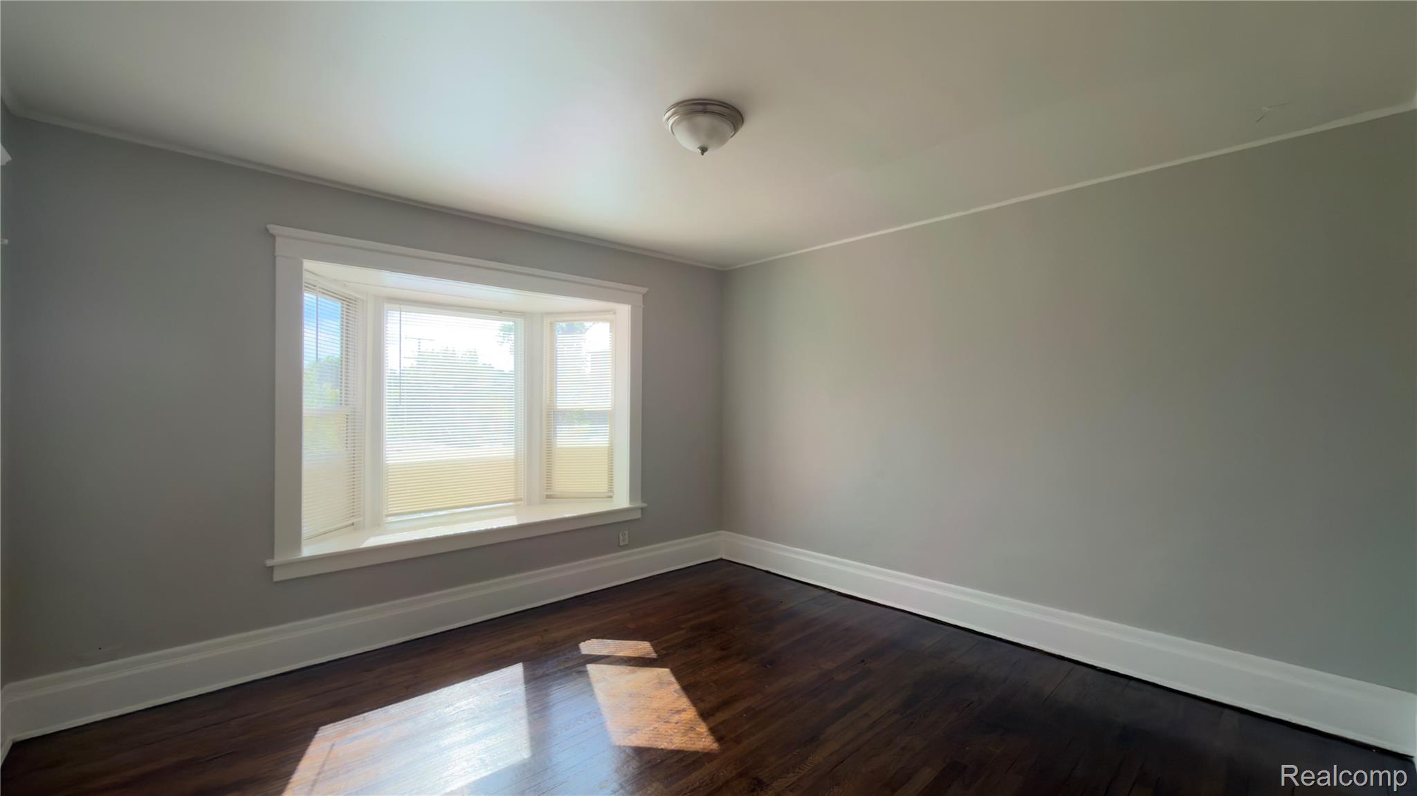 9426 John R Street Detroit, MI 48202 - Photo 13 of 17 Bay window with white trim, wood-finish flooring, and light gray walls