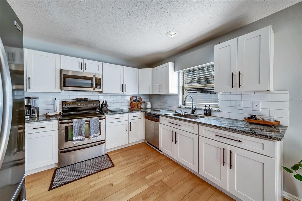 13706 Fareham Road Odessa, FL 33556 - Photo 8 of 21 a kitchen with granite countertop white cabinets and stainless steel appliances
