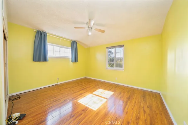 a view of empty room with wooden floor and fan