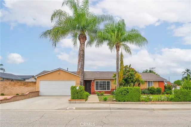 a front view of a house with a yard and palm trees
