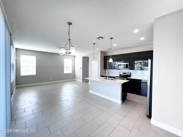 a large kitchen with kitchen island granite countertop a stove a sink a window and a counter space