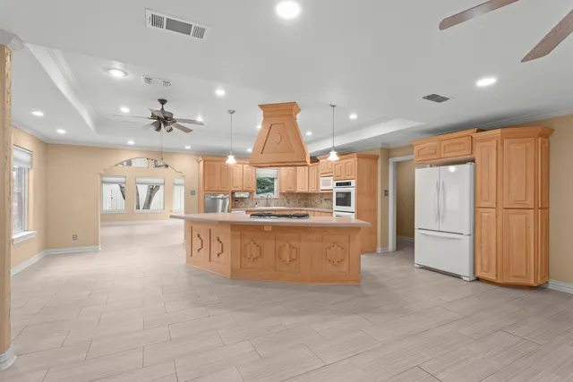 a large kitchen with granite countertop a large counter top stainless steel appliances and cabinets