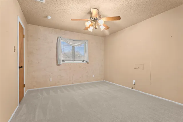 an empty room with a chandelier fan and a ceiling fan