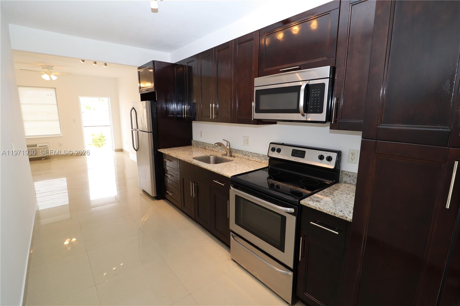 540 74th Street, Unit 10 Miami Beach, FL 33141 - Photo 2 of 27 a kitchen with stainless steel appliances a stove a microwave and a refrigerator