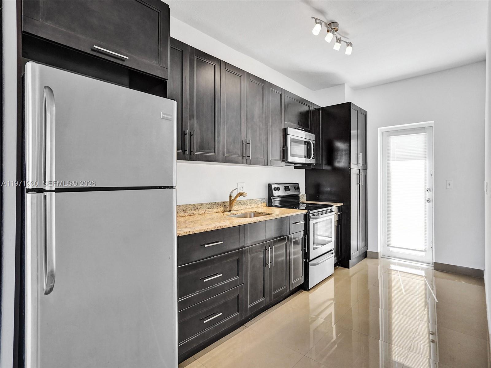 540 74th Street, Unit 10 Miami Beach, FL 33141 - Photo 3 of 27 a kitchen with stainless steel appliances granite countertop a refrigerator a sink and a stove