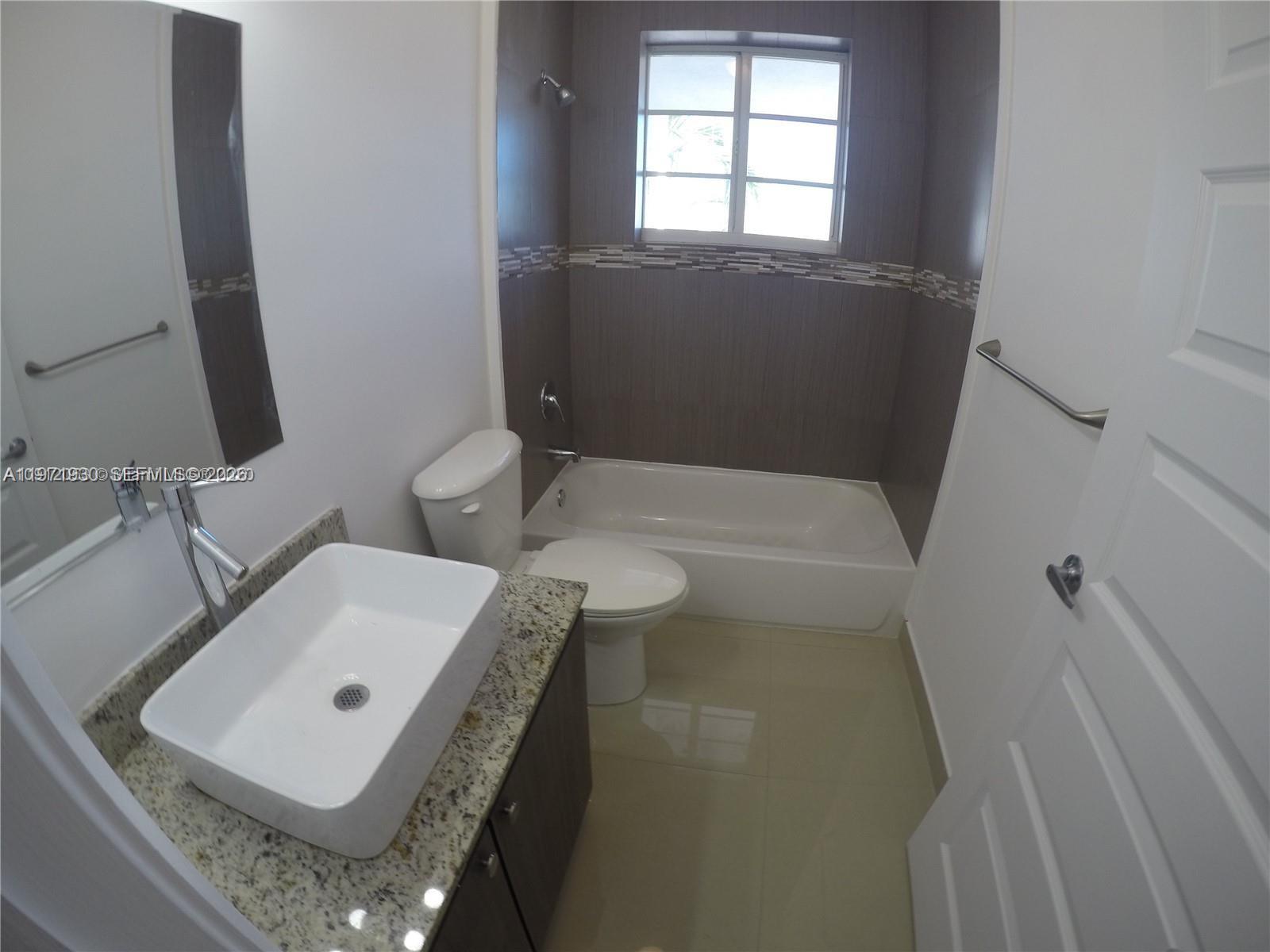 540 74th Street, Unit 10 Miami Beach, FL 33141 - Photo 10 of 27 a bathroom with a sink toilet and window