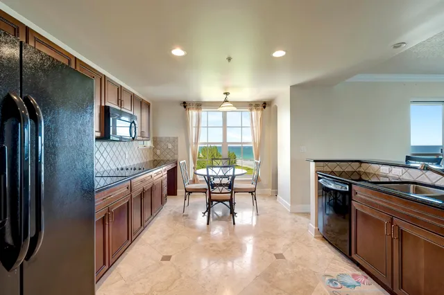 a kitchen with stainless steel appliances granite countertop a table chairs refrigerator and microwave