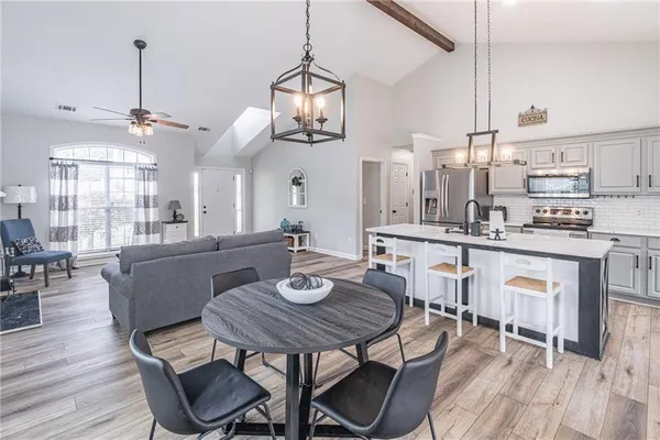 a dining room with wooden floor a chandelier a wooden table and chairs