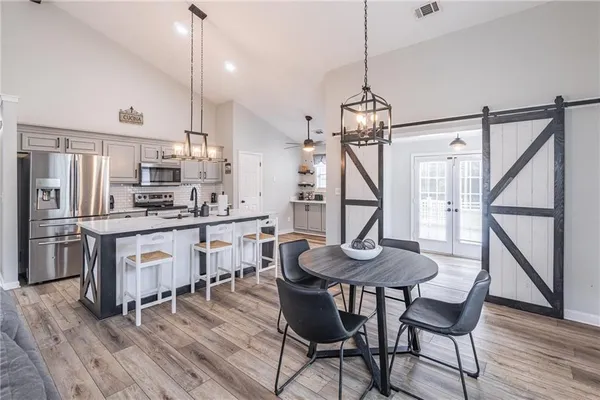 a kitchen with granite countertop a table chairs stainless steel appliances and wooden floor