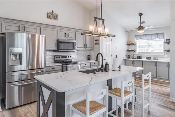 a kitchen with stainless steel appliances granite countertop a refrigerator a stove a sink dishwasher a dining table and chairs with wooden floor