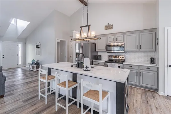 a kitchen with stainless steel appliances a dining table chairs stove and cabinets