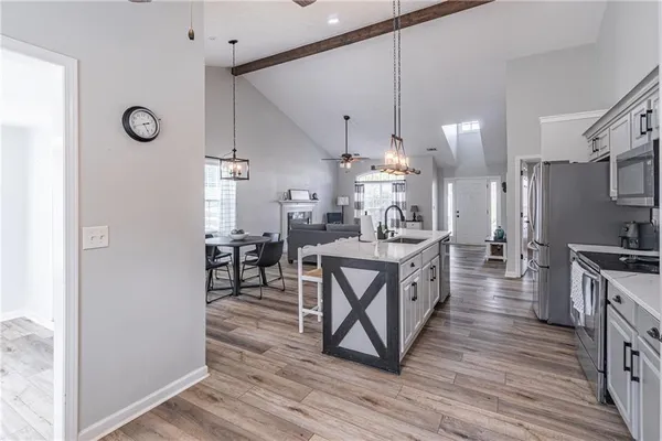 a kitchen with stainless steel appliances a table chairs refrigerator and cabinets