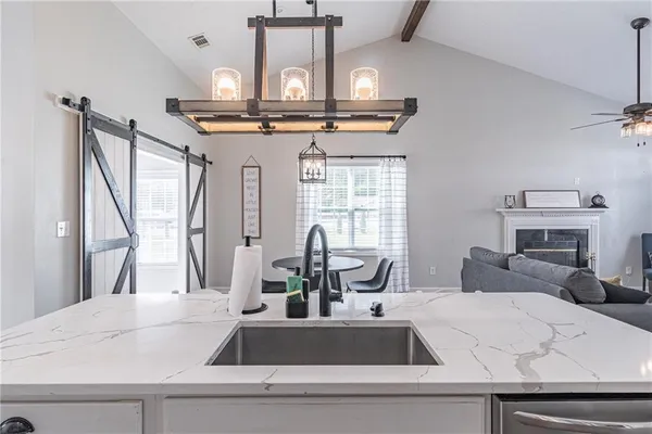 a kitchen with a sink a counter top space and living room view