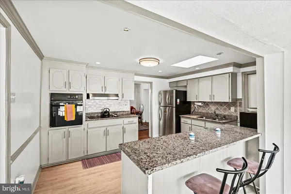 a kitchen with stainless steel appliances granite countertop a refrigerator and a stove top oven
