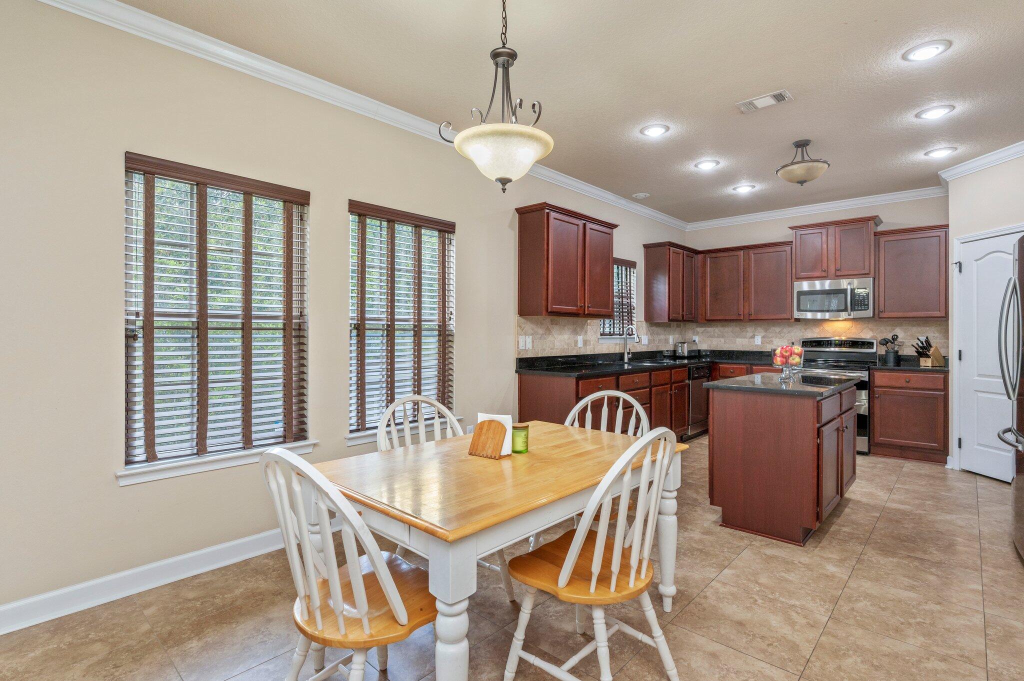 4558 Hermosa Road Crestview, FL 32539 - Photo 13 of 48 a dining room with kitchen island stainless steel appliances furniture a large window and kitchen view