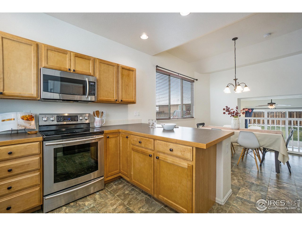 4386 Cypress Ridge Lane Wellington, CO 80549 - Photo 7 of 30 a kitchen with stainless steel appliances kitchen island granite countertop a stove top oven a sink dishwasher a dining table and chairs with wooden floor